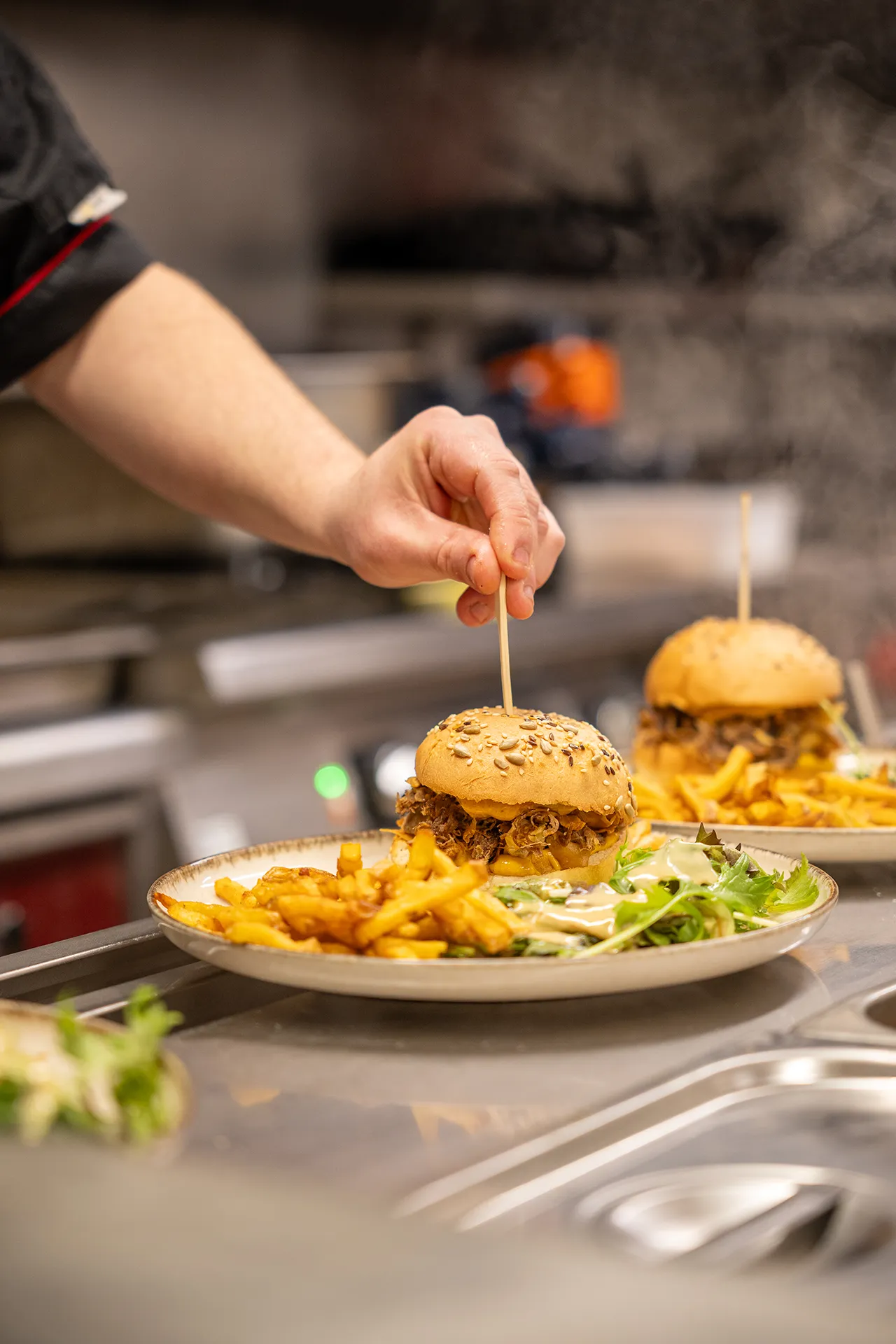 Préparation d'un burger dans la cuisine du restaurant Rosière